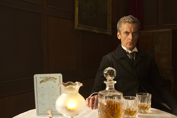 The Doctor (Peter Capaldi) sits at table looking into adrian rogers's camera
